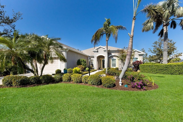 mediterranean / spanish house with a front yard, an attached garage, and stucco siding