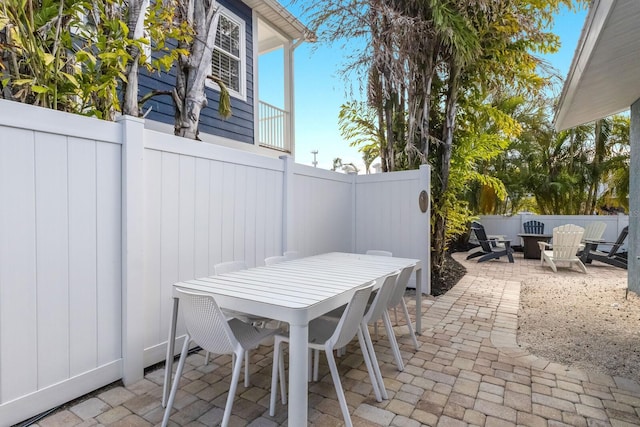 view of patio / terrace with a fire pit, outdoor dining area, and fence