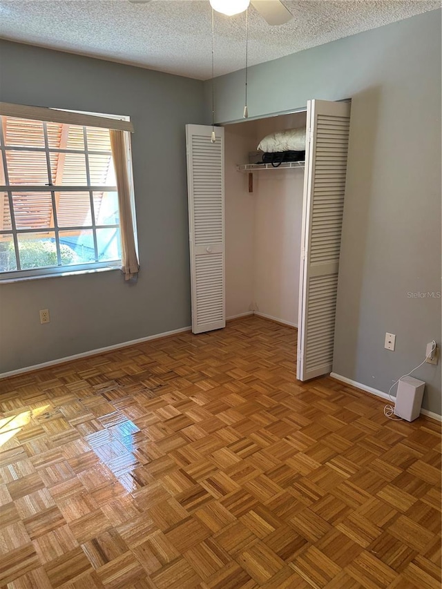 unfurnished bedroom with a textured ceiling, a closet, and baseboards