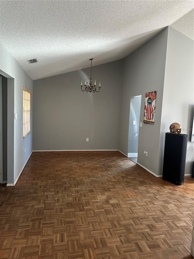 empty room featuring baseboards, visible vents, lofted ceiling, a textured ceiling, and a chandelier