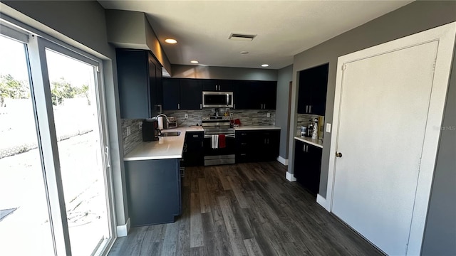 kitchen featuring visible vents, dark wood-type flooring, stainless steel appliances, dark cabinetry, and light countertops