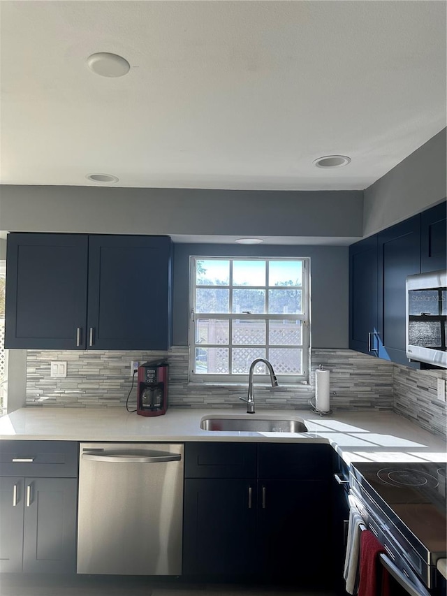 kitchen with blue cabinets, stainless steel appliances, a sink, and light countertops