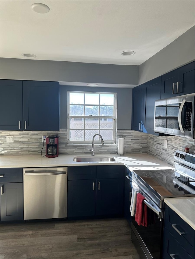 kitchen with blue cabinets, a sink, light countertops, appliances with stainless steel finishes, and tasteful backsplash