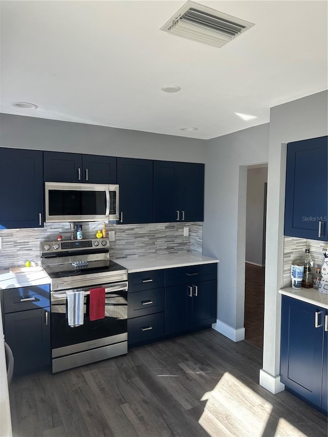 kitchen with blue cabinets, stainless steel appliances, visible vents, light countertops, and dark wood finished floors