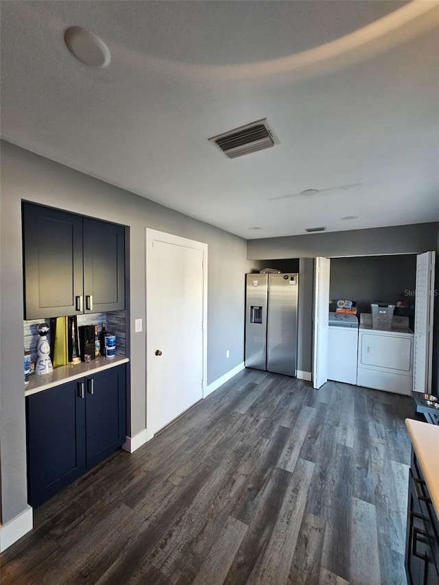 kitchen with stainless steel fridge, visible vents, dark wood-style flooring, independent washer and dryer, and light countertops