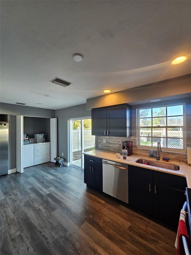 kitchen featuring appliances with stainless steel finishes, washer and clothes dryer, a sink, and light countertops