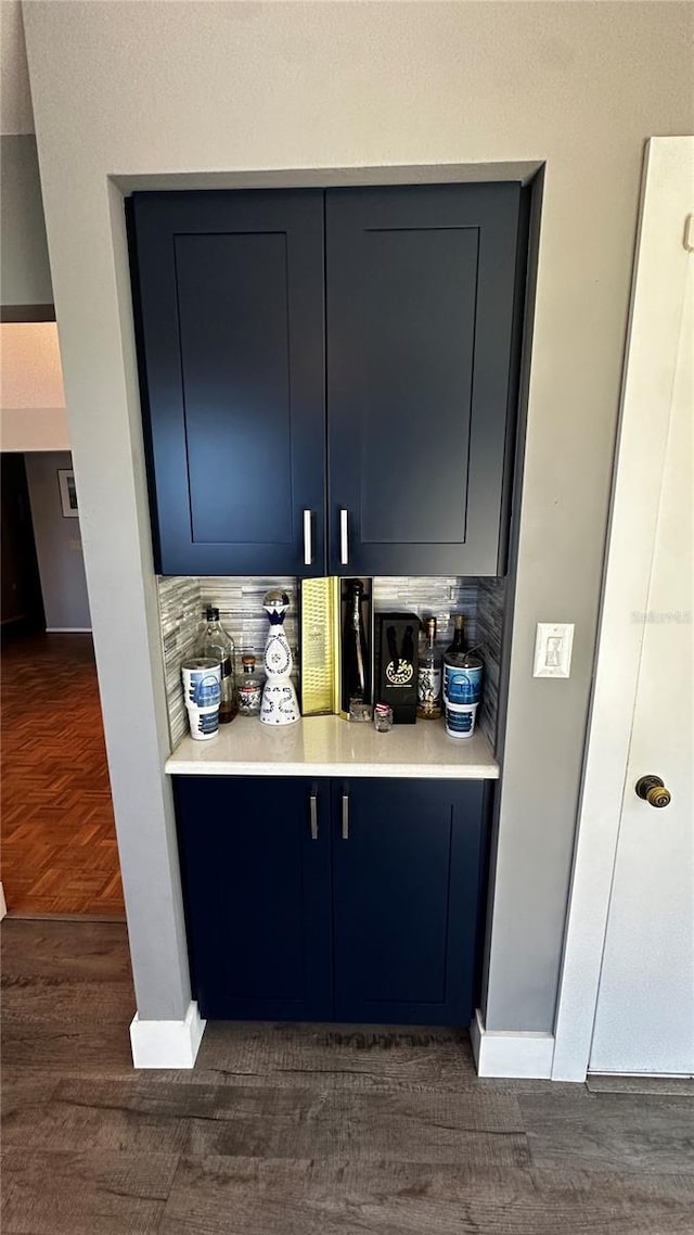 bar with dark wood-type flooring, baseboards, and tasteful backsplash