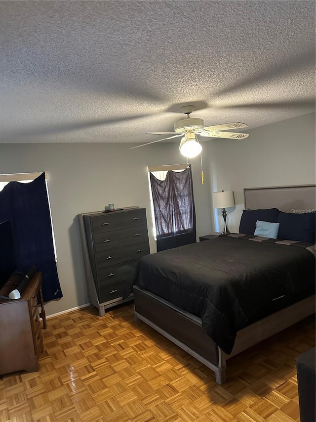 bedroom featuring ceiling fan, baseboards, and a textured ceiling