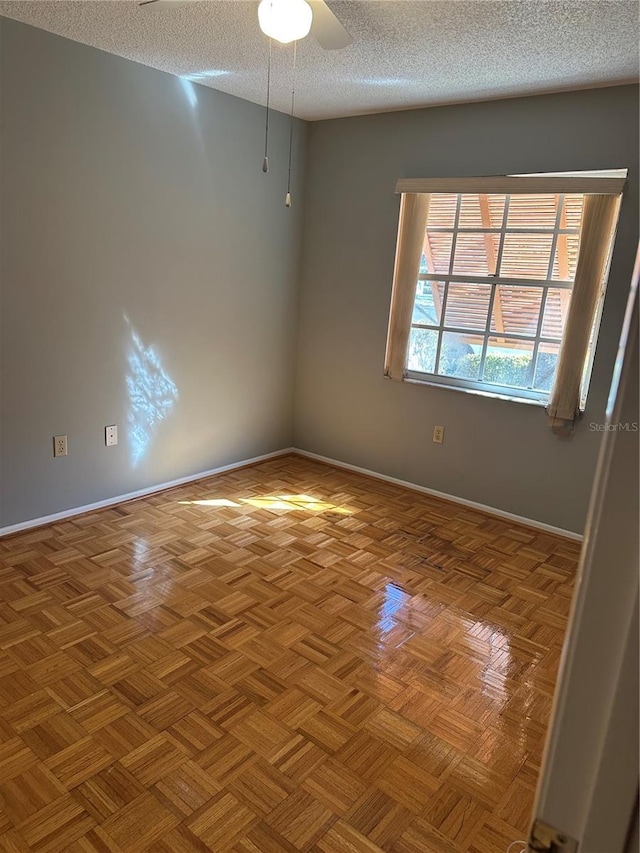 empty room featuring ceiling fan, a textured ceiling, and baseboards