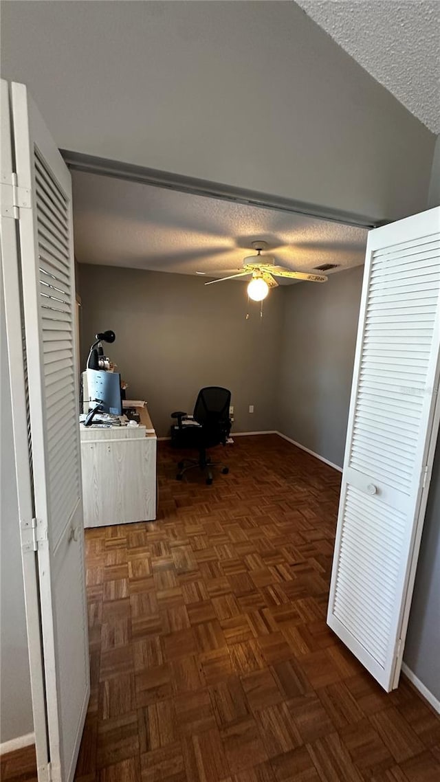 unfurnished office featuring ceiling fan, baseboards, and a textured ceiling