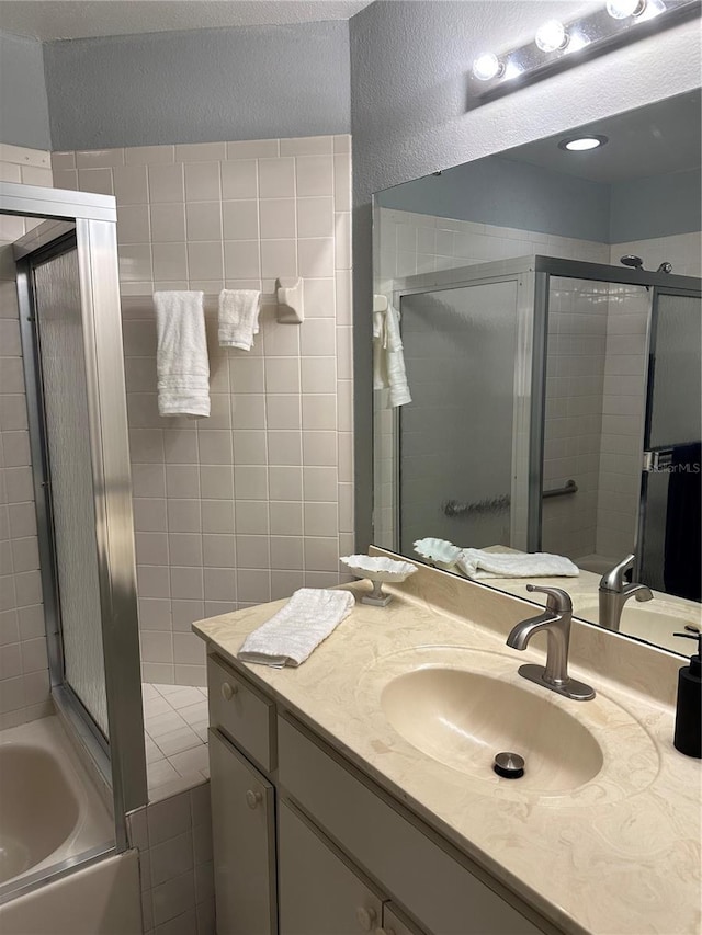 full bathroom featuring a garden tub, a textured wall, a shower stall, and vanity