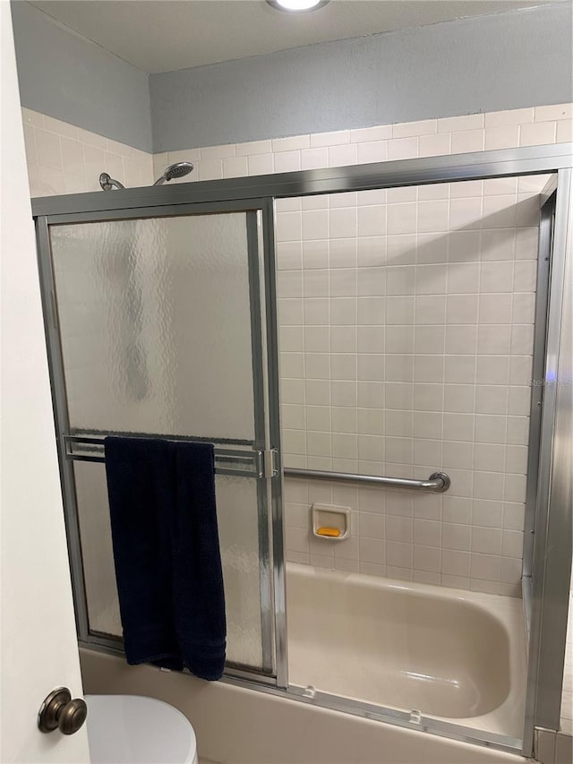 full bathroom with toilet and bath / shower combo with glass door