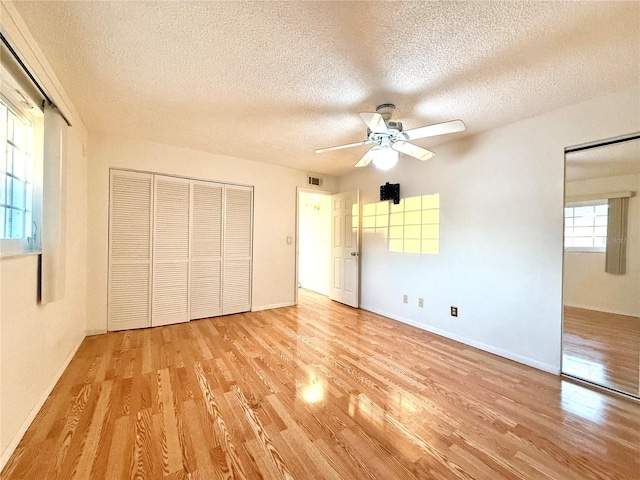 unfurnished bedroom with light hardwood / wood-style flooring, a textured ceiling, and a closet