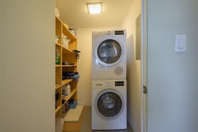 clothes washing area featuring stacked washer and clothes dryer and laundry area