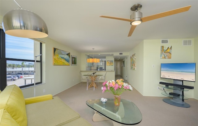 carpeted living area with visible vents and a ceiling fan