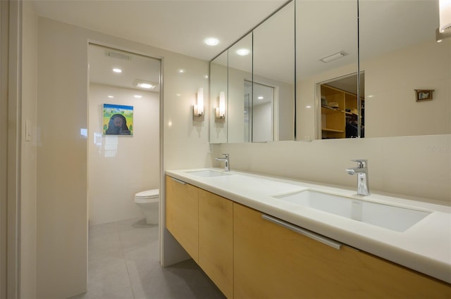 full bathroom featuring double vanity, tile patterned flooring, a sink, and toilet