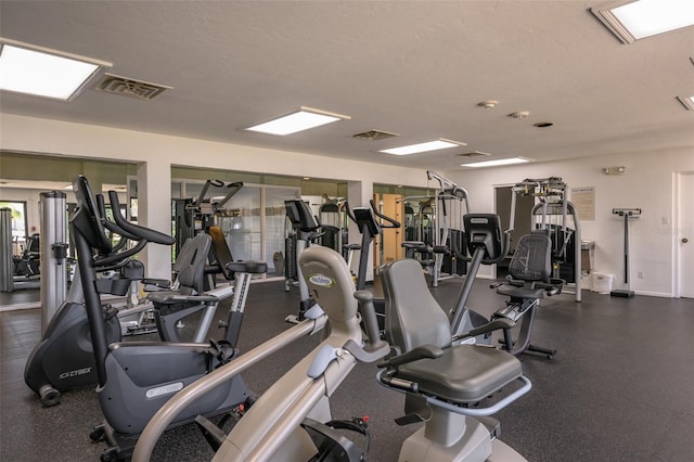 workout area featuring baseboards, visible vents, and a textured ceiling