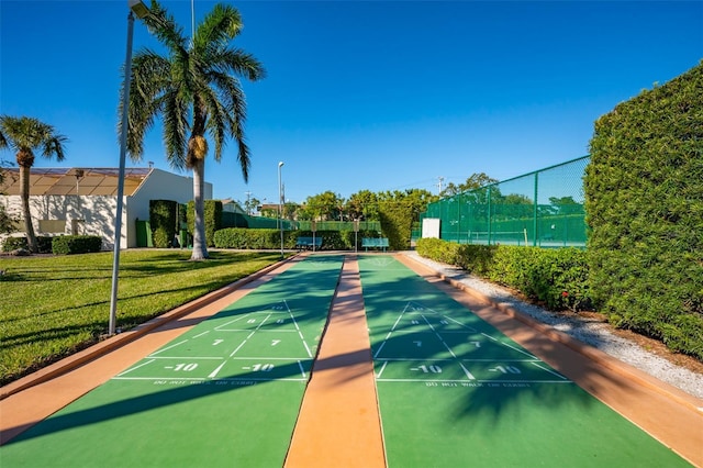 view of property's community featuring a yard, fence, and shuffleboard