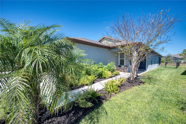 view of home's exterior featuring a garage, fence, a lawn, and stucco siding