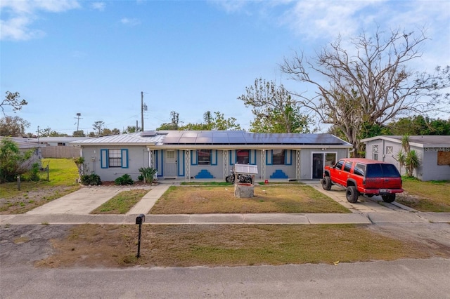 ranch-style house featuring driveway, a front lawn, fence, and roof mounted solar panels