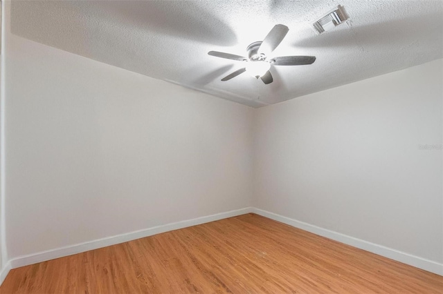 spare room with light wood-style flooring, a textured ceiling, visible vents, and baseboards