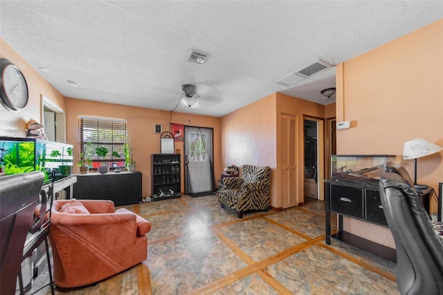 living area with a textured ceiling, visible vents, and a ceiling fan