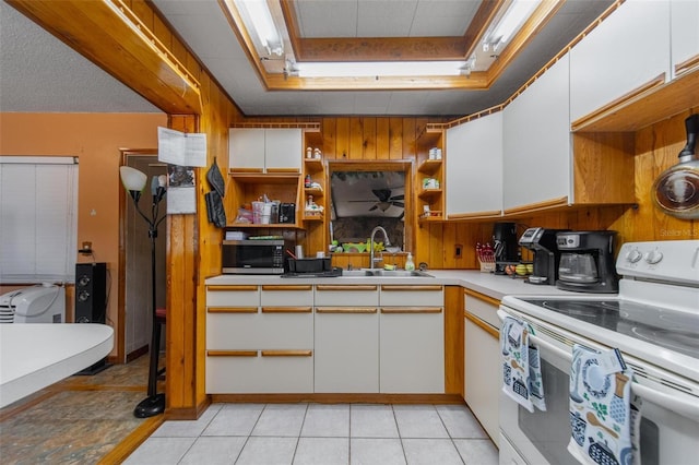 kitchen featuring white range with electric cooktop, white cabinets, stainless steel microwave, open shelves, and a sink