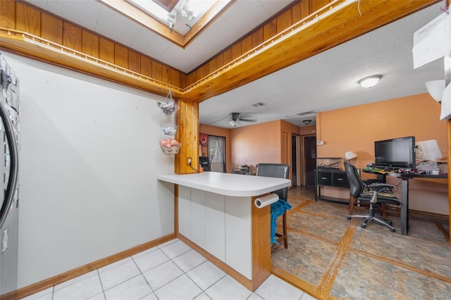 kitchen with open floor plan, ceiling fan, a breakfast bar area, and baseboards