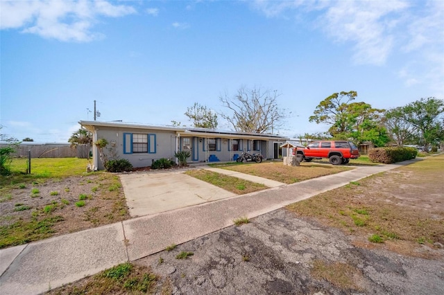 view of front of home featuring a front yard, fence, and roof mounted solar panels