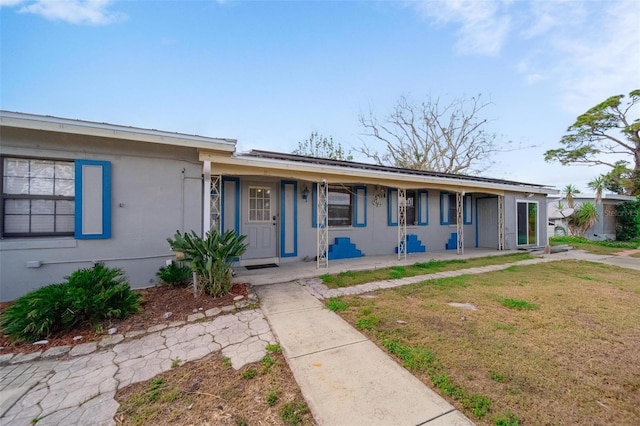 single story home with a front lawn, a porch, and stucco siding