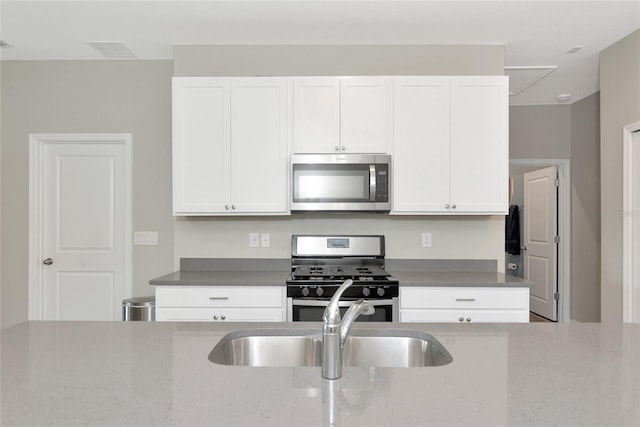 kitchen featuring white cabinetry, sink, stainless steel appliances, and light stone counters