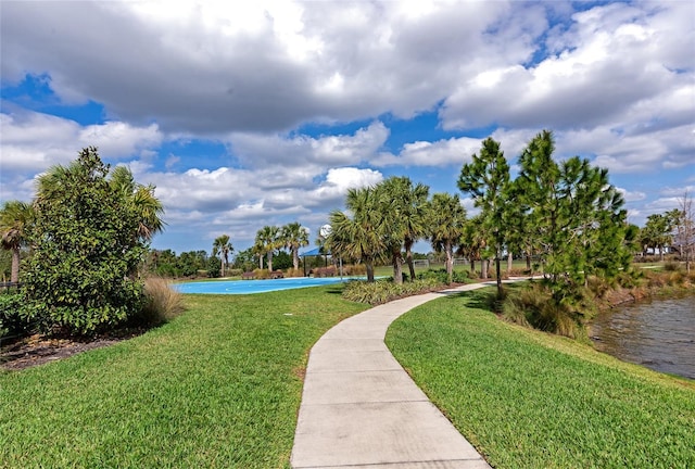 view of home's community with a water view and a lawn