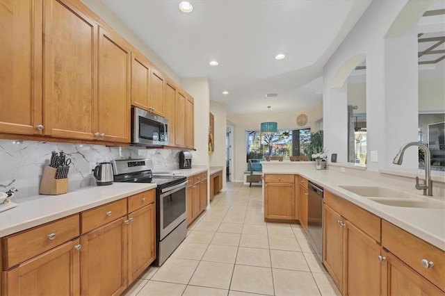 kitchen featuring light tile patterned floors, sink, backsplash, stainless steel appliances, and kitchen peninsula