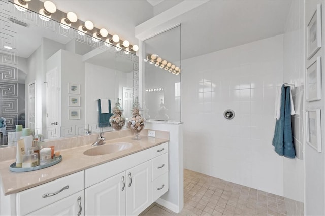 bathroom with tiled shower and vanity