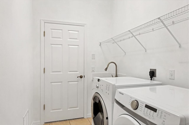 clothes washing area with washing machine and clothes dryer and light tile patterned floors