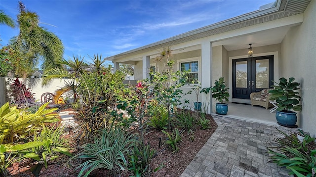 view of exterior entry with french doors, fence, and stucco siding