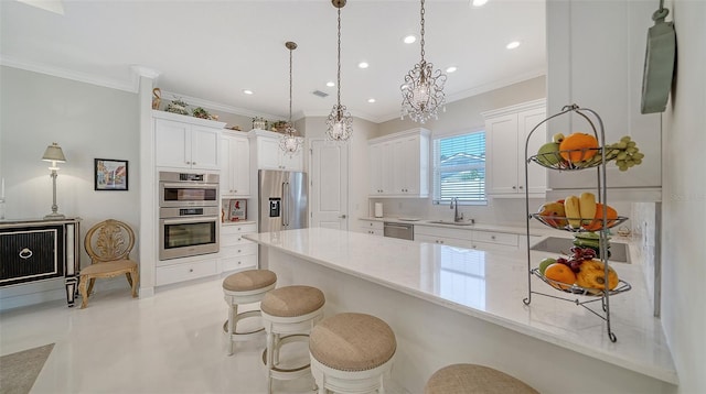 kitchen with white cabinets, hanging light fixtures, stainless steel appliances, a kitchen bar, and a sink