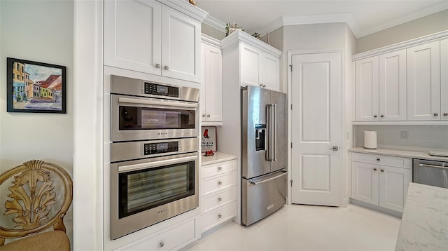 kitchen featuring light stone countertops, white cabinetry, appliances with stainless steel finishes, and ornamental molding