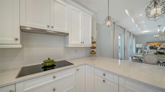 kitchen featuring black electric stovetop, under cabinet range hood, white cabinetry, hanging light fixtures, and light stone countertops