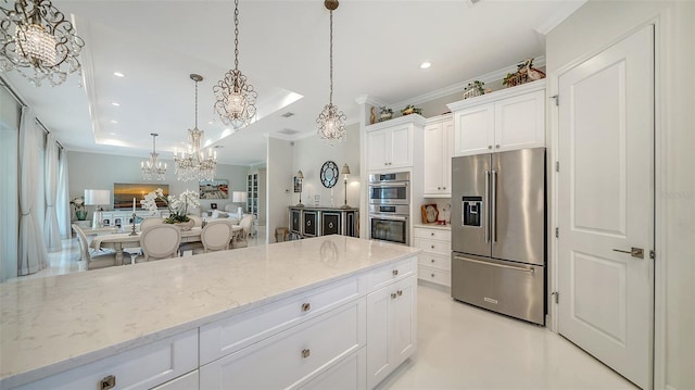 kitchen with light stone counters, a tray ceiling, hanging light fixtures, appliances with stainless steel finishes, and white cabinets