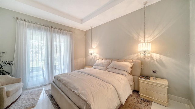 bedroom with a raised ceiling and baseboards