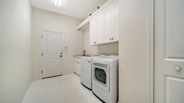 clothes washing area with cabinet space, baseboards, and washer and clothes dryer