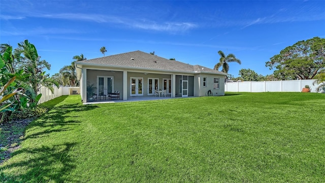 back of house featuring a patio area, french doors, a fenced backyard, and a yard