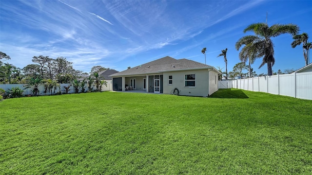 back of house featuring a fenced backyard, a lawn, a patio, and stucco siding