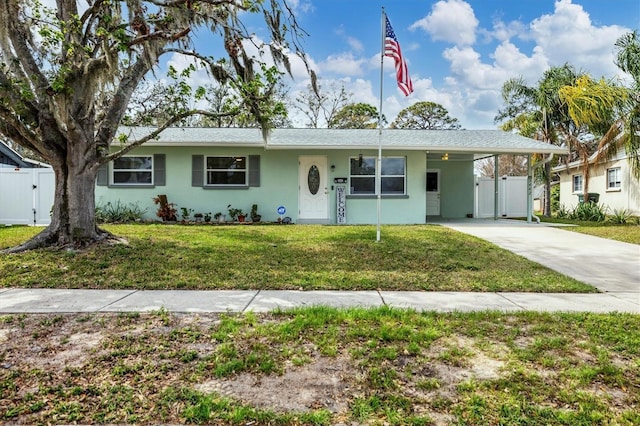 ranch-style home with driveway, a front lawn, a carport, and stucco siding