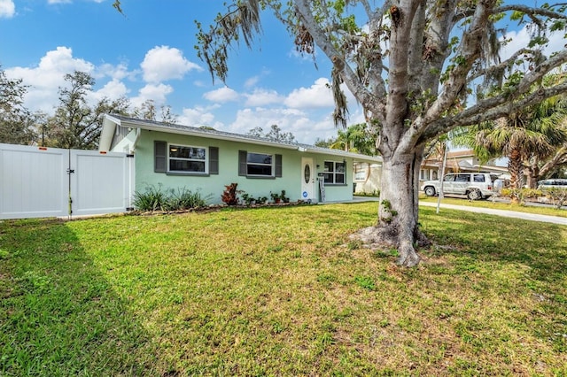 ranch-style home featuring a front yard, a gate, and stucco siding