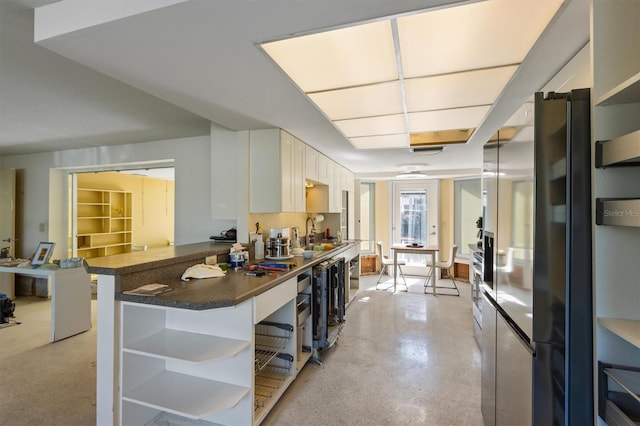 kitchen featuring a breakfast bar area, sink, white cabinetry, stainless steel fridge with ice dispenser, and kitchen peninsula