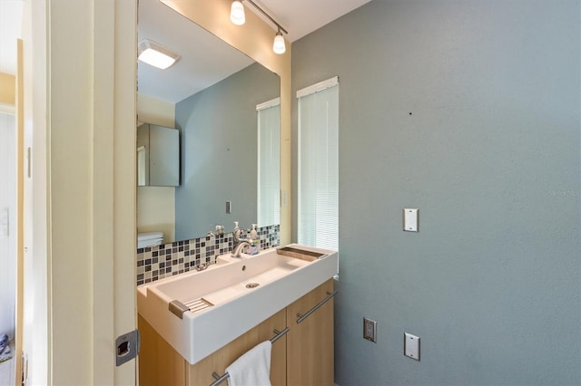 bathroom with track lighting, decorative backsplash, and vanity