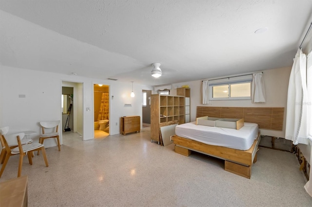 bedroom with ceiling fan, connected bathroom, and a textured ceiling