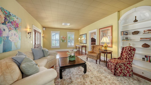 living room with built in features, visible vents, baseboards, and wood finished floors